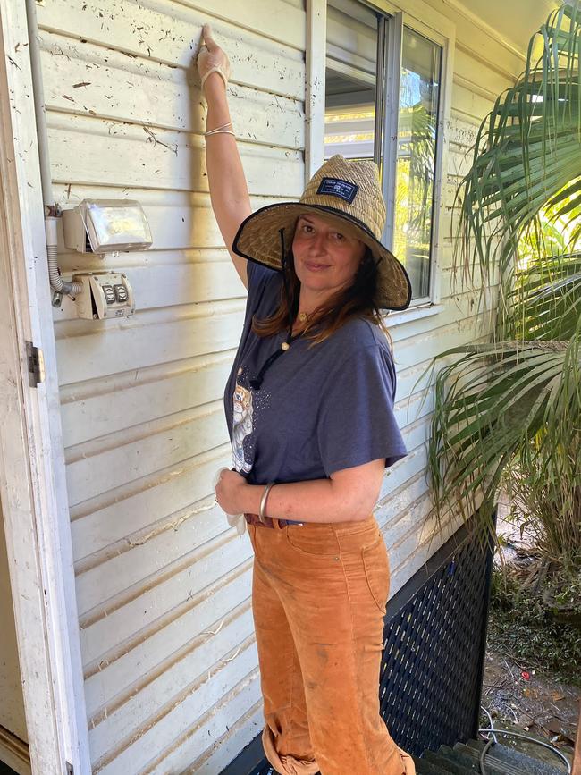 Ms Daley shows how high the floodwaters reached at her East Lismore home.