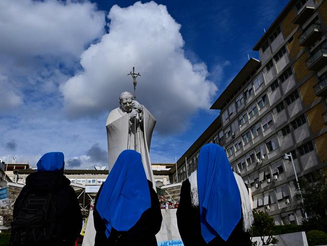 Nuns pray at the statue of John Paul II at the Gemelli University Hospital where Pope Francis is hospitalised with pneumonia, in Rome on February 28, 2025. (Photo by Tiziana FABI / AFP)