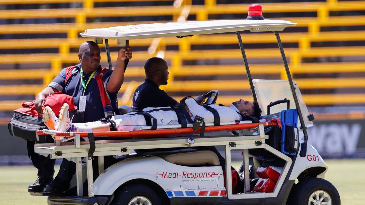Keshav Maharaj (R) is taken off the field by medical staff. (Photo by PHILL MAGAKOE / AFP)