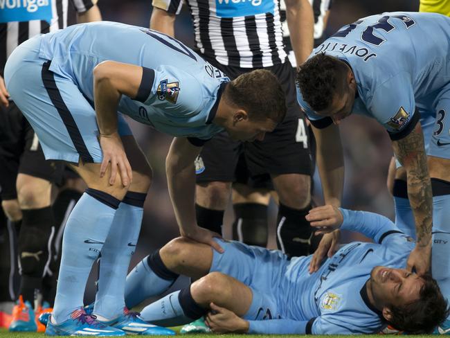 Manchester City's Edin Dzeko, left, and Stevan Jovetic stand over an injured Silva. Picture: Jon Super/AP