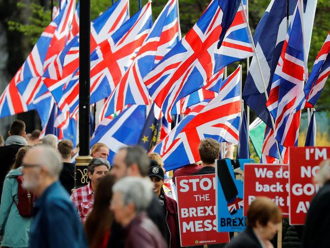 Brexit activists flie Union flags as anti-Brexit activists hold placards as they demonstrate near the Houses of Parliament in Westminster, London on March 28, 2019. - The British government said it intended to put Prime Minister Theresa May's twice-rejected Brexit deal to a third parliamentary vote on Friday to avoid a chaotic no-deal divorce from the EU in two weeks. May's throw of the dice comes a day after her dramatic pledge to resign in order to persuade her rivals to finally back her vision for breaking Britain's 46-year bond with the European project. (Photo by Tolga AKMEN / AFP)