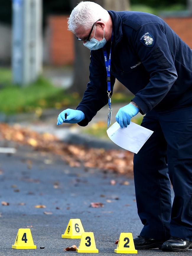 A forensic officer picks up a bullet casing after a drive-by shooting.