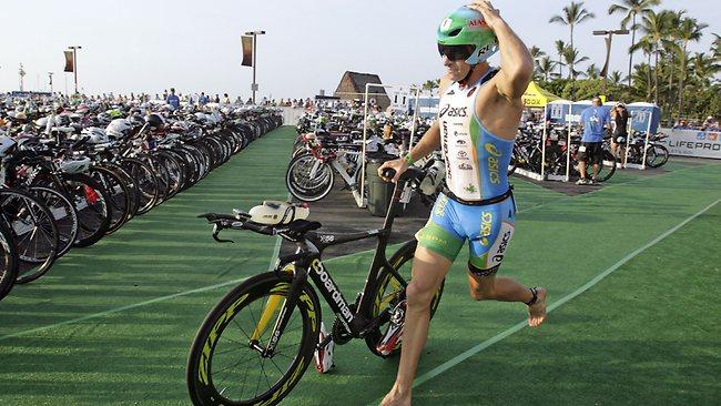 Defending champion Pete Jacobs runs with his bike during the 2013 Ironman World Championship triathlon in Hawaii.