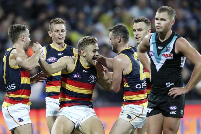 Adelaide’s Hugh Greenwood snaps a goal and celebrates with team mates Jordan Gallucci, Brad Crouch and David McKay as Power defender Dan Houston walks past. in Showdown 46 at Adelaide Oval. Picture SARAH REED