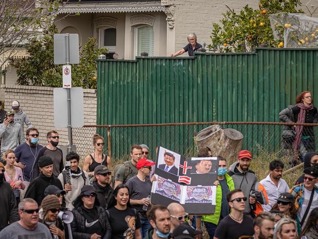 A resident looks on as anti-lockdown protesters march through Richmond. Picture: Jason Edwards