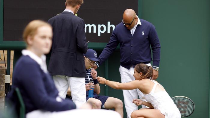 Jodie Burrage helps a ball boy after they fainted during her Ladies' singles first round match against Lesia Tsurenko during day one of the 2022 Wimbledon Championships at the All England Lawn Tennis and Croquet Club, Wimbledon. Picture date: Monday June 27, 2022. (Photo by Steven Paston/PA Images via Getty Images)