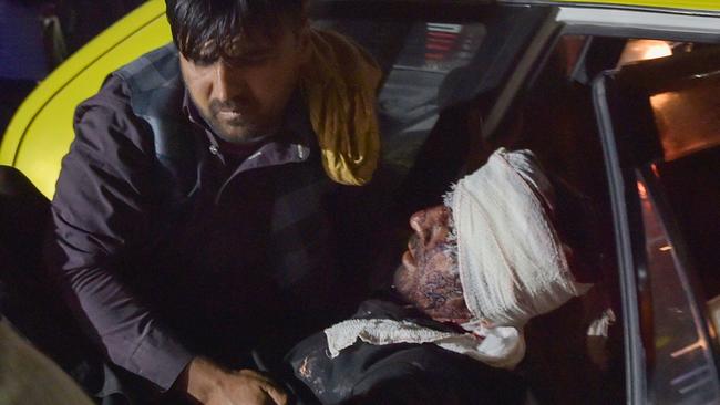 Medical and hospital staff carry an injured man out of a car for treatment after two blasts detonated outside Kabul airport. Picture: AFP