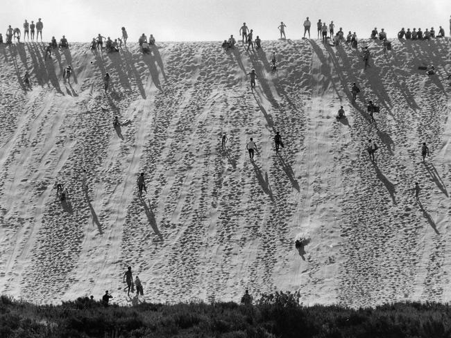 People and children slide down the monster sandhill at Port Noarlunga in the 1960s.