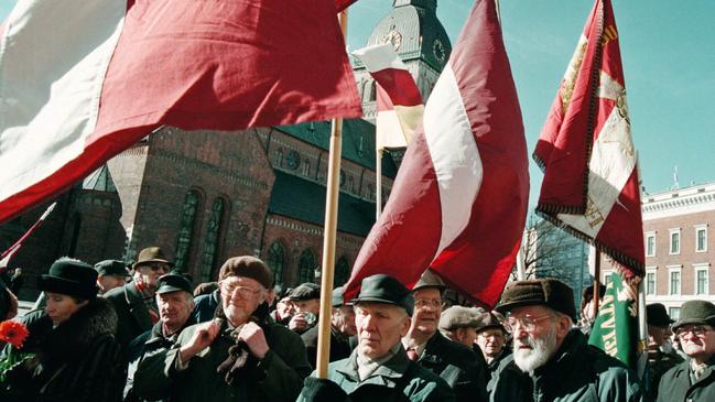 Veterans of the Latvian Nazi Waffen SS carry Latvian flags, as they march to remember their fallen comrades, in Riga, Latvia in 2000. Picture: AP