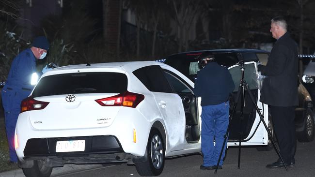 Detectives examine a car at the scene.