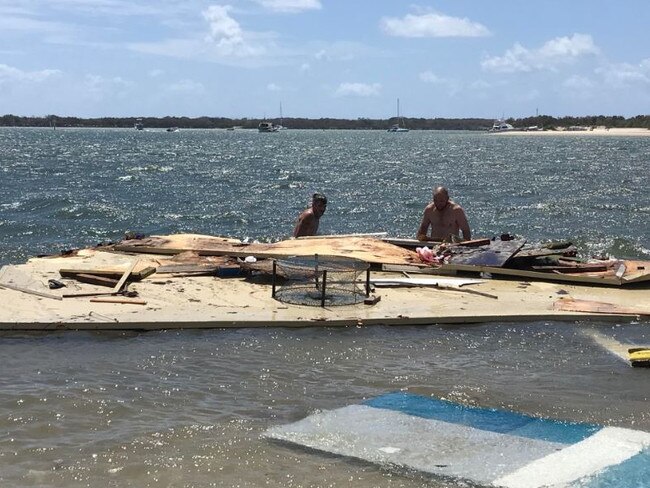 Two men trying to remove parts of the collapsed houseboat from the water. Photo: Emily Halloran