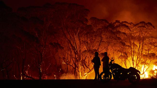 Residents look on as flames burn through bush at Lake Tabourie. Picture: Brett Hemmings/Getty Images