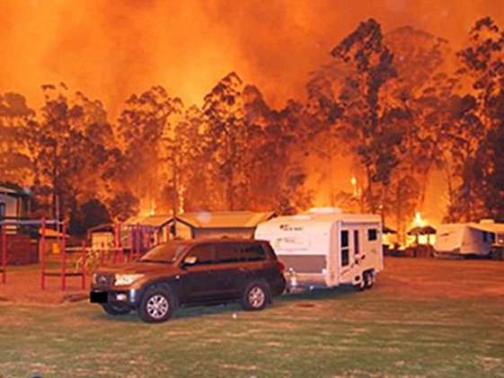 Firefighters move a caravan as flames bear down on Glen Cromie Caravan Park in Drouin. Picture: Bushfires Royal Commission statement of Matt Ahern   