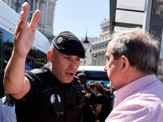 A Spanish policeman tries to keep people calm as they queue to catch a bus at the Plaza de Cibeles during a massive power cut affecting the entire Iberian peninsula and the south of France, in Madrid on April 28, 2025. A 