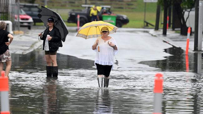 People walking through water in Collingwood St, Albion on Monday. Picture: John Gass