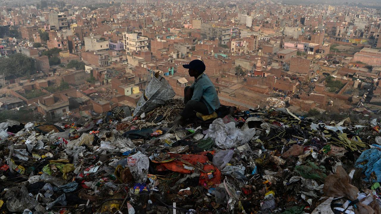 A young Indian ragpicker looks over the city after collecting usable material from a garbage dump at the Bhalswa landfill site in New Delhi. Picture: AFP