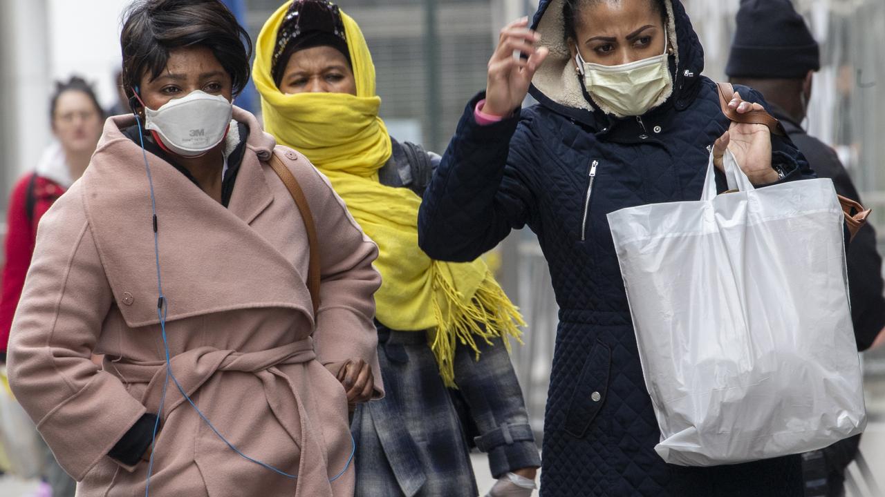 Women wear face masks and a scarf to protect themselves as they walk along 34th St in New York. Picture: AP Photo/Mary Altaffer