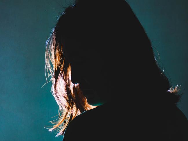 silhouette of depress woman standing in the dark with light shine behind