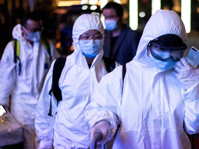 TOPSHOT - Passengers wear hazmat suit as they arrive at the Wuhan Wuchang Railway Station in Wuhan, to leave the city in China's central Hubei province early on April 8, 2020. - Thousands of Chinese travellers flocked to catch trains leaving coronavirus-ravaged Wuhan early April 8, as authorities lifted a more than two-month ban on outbound travel from the city where the global pandemic first emerged. (Photo by NOEL CELIS / AFP)