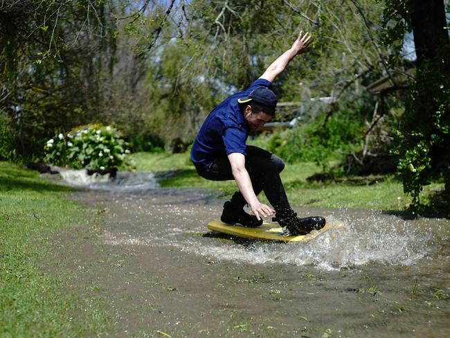 Kyle Brand took photos of his brother Daniel Brand attempting to surf in their flooded yard in Willunga South. Picture: Donna Chess