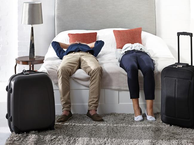 Indoor shot of mature couple lying on bed with luggage