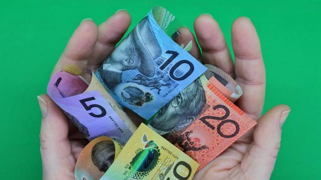 POV (point of view) of a person holding Australian dollar currency bank notes with his two hands isolated on a green background. ; share dividends generic