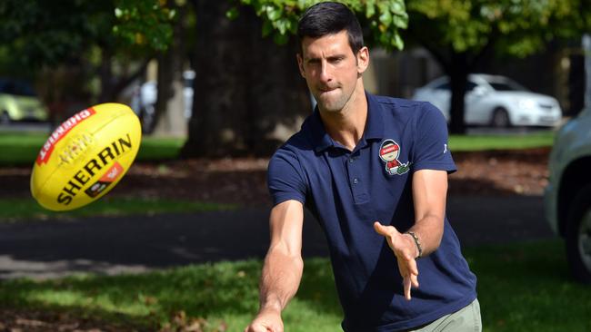 Novak Djokovic plays with a rugby ball at the end of two-week quarantine in Adelaide today. Then withdrew from an exhibition match 15 minutes before it was due to start. Picture: Brenton Edwards/AFP