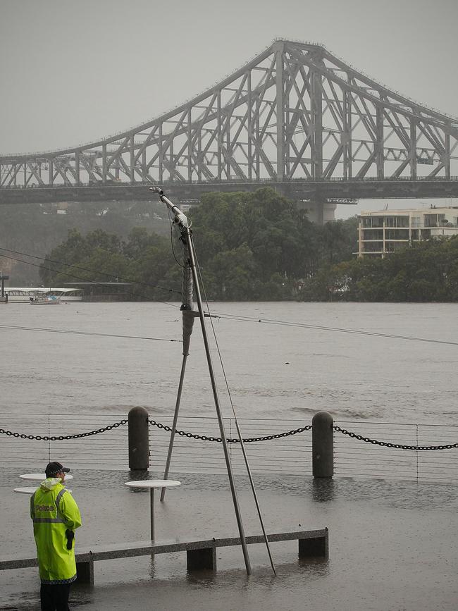 A Queensland Police officer watches the flooded Brisbane River adjacent the Eagle Street Pier walkway in Brisbane’s CBD, January 11, 2011.