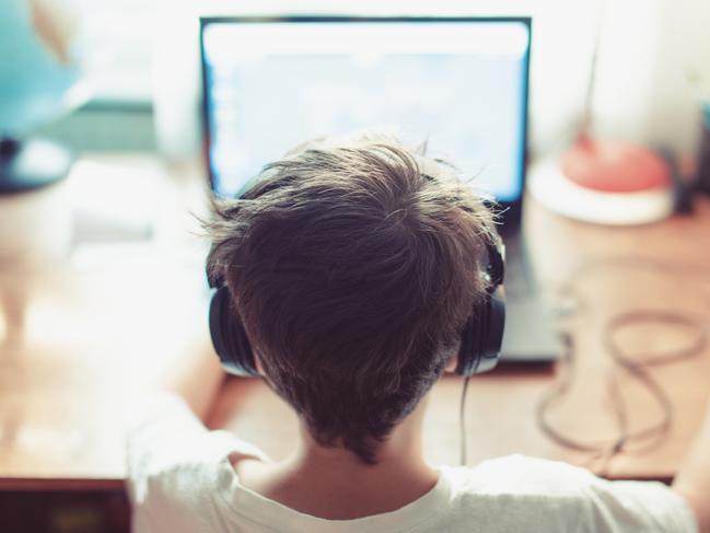 Little dependent gamer kid playing on laptop indoors. iStock