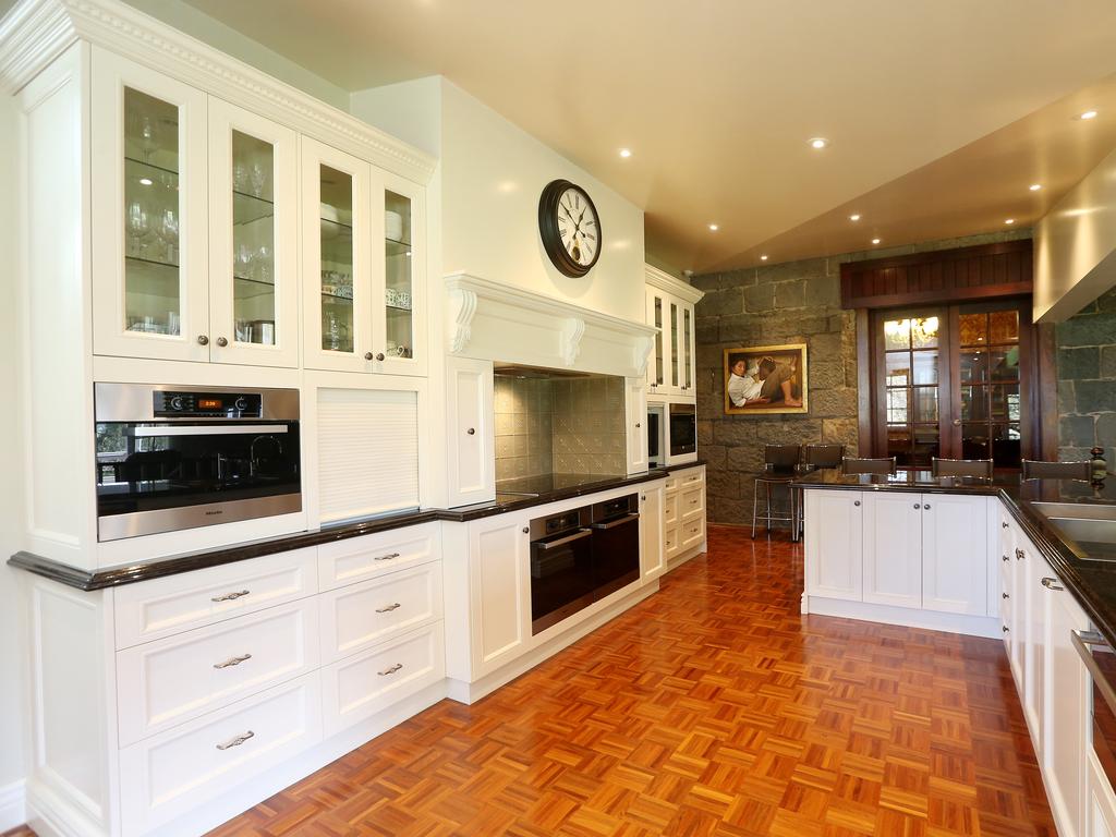 An open-plan kitchen, dining and living zone feature a fireplace and window that frames views of the garden and floods the room with natural light. Picture: Andy Rogers