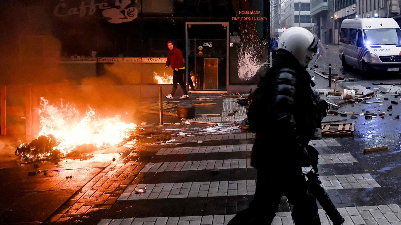 A Belgian riot policeman runs past a fire during clashes with police. Picture: AFP)