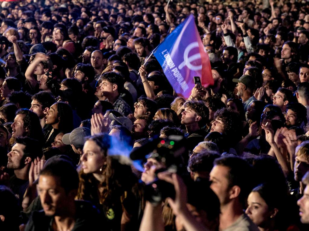A supporter wave a flag of L'Union Populaire movement as members of the left coalition Nouveau Front Populaire stand on stage during a rally. Picture: AFP