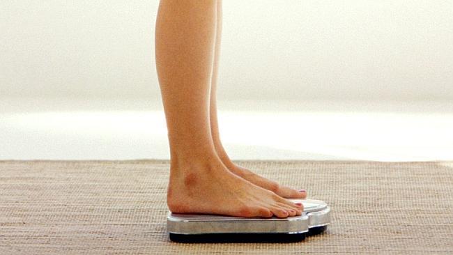  side profile of a woman standing on a weighing scale 