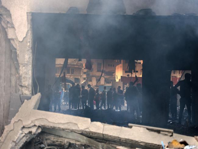 TOPSHOT - People gather as smoke rises from a UN school-turned-shelter after it was hit in an Israeli strike, in the Rimal neighbourhood of Gaza City in the northern Gaza Strip on November 14, 2024, amid the ongoing war between Israel and the Hamas militant group. (Photo by Omar AL-QATTAA / AFP)