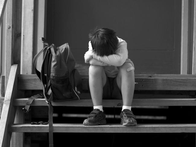 Boy sitting in the doorway of his classroom after being bullied