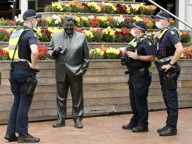 Police have a chat with Bart Cummings’ statue before the racing action kicks off. Picture: Darrian Traynor