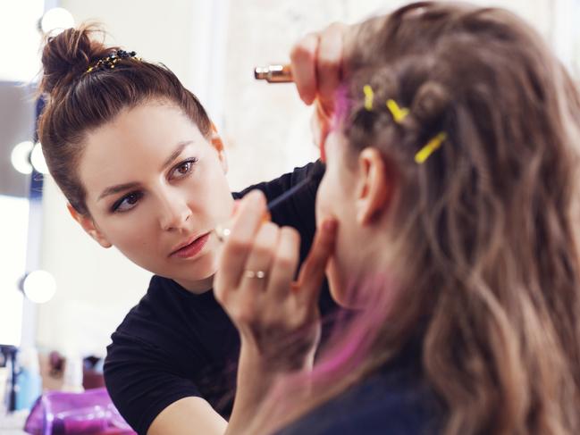 Make-up artist applying mascara on model's eyelashes, selective focus on make up artist