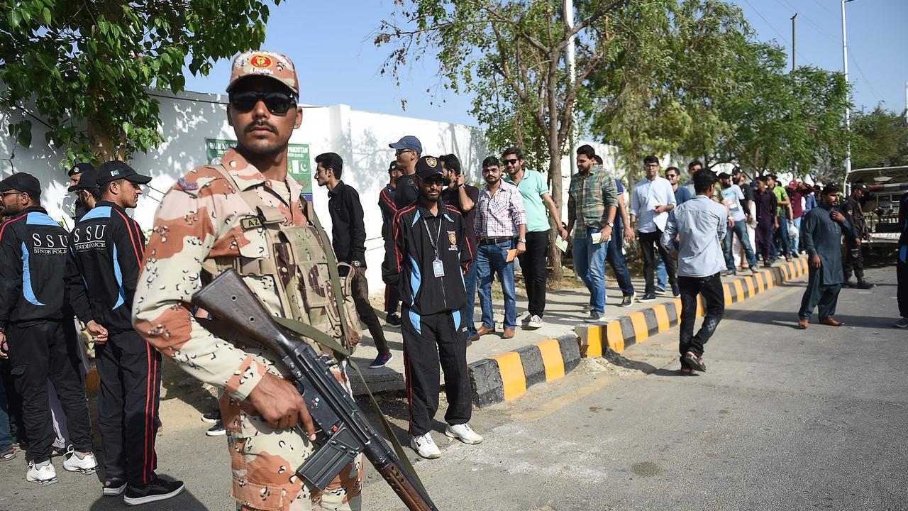 A Pakistani ranger stands guard as cricket fans line-up at security checkpoint outside the National Stadium.