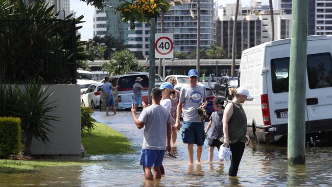 Flooding from the King tide at Budds Beach at Surfers Paradise was made worse by the approaching storm system. People wading through the floodwaters. Picture Glenn Hampson
