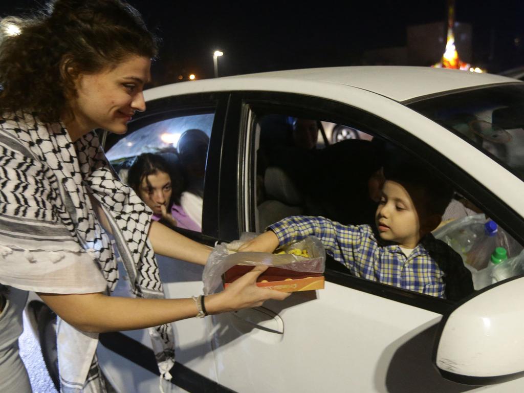 A woman passes out sweets to passers by in Damascus on October 7, 2023, to express their solidarity with Palestine. Picture: AFP