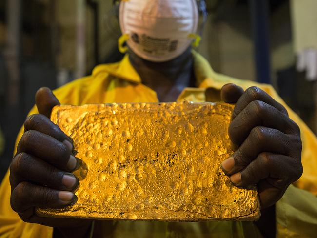 A mine worker displays a large ingot of gold after cleaning and hammering it during the refining process at the production plant for the Loulo-Gounkoto gold mine complex operated by Randgold Resources Ltd. in Loulo, Mali, on Friday, Nov. 1, 2013. Randgold Resources Ltd., a producer of the precious metal in Africa, said there are opportunities to acquire mines on the continent as the biggest companies in the industry scale back operations in the face of lower prices. Photographer: Simon Dawson/Bloomberg via Getty Images