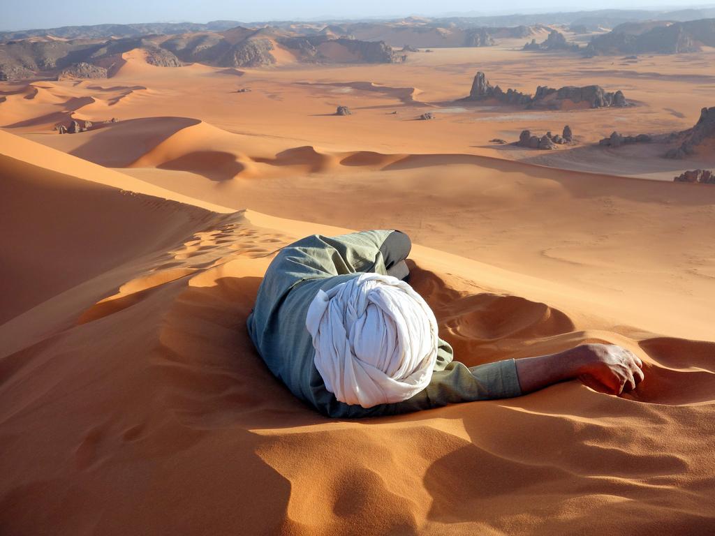 “A well earned rest in the Sahara” by Evan Cole / National Geographic Traveler Photo Contest. This photo, of Moussa Macher, our Touareg guide, was taken at the summit of Tin-Merzouga, the largest dune (or erg) in the Tadrat region of the Sahara desert in southern Algeria. Moussa rested while waiting for us to finish our 45 minute struggle to the top. It only took 10 minutes of rolling, running and jumping to get to get back down. Location: Summit of Tin-Merzouga, Tadrat, Tassili N’Ajjer National Park, Algeria. Picture: <a href="http://travel.nationalgeographic.com/travel/traveler-magazine/photo-contest/2014" target="_blank">National Geographic Photo Contest </a>