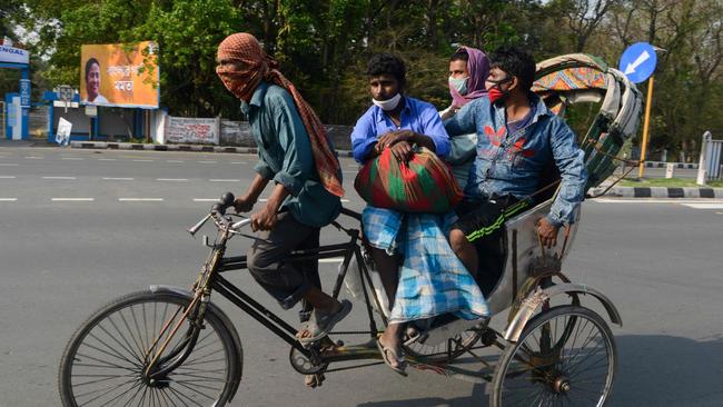 Migrant workers with their belongings ride on a rickshaw to leave the town for their village. Picture: Diptendu Dutta/AFP