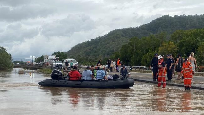 Cairns flood 2023: Royal Australian Navy personnel work with civilian emergency services to evacuate members of the public from Holloways Beach using a stretch of the Captain Cook Highway near the Barron River Bridge. Picture: Supplied