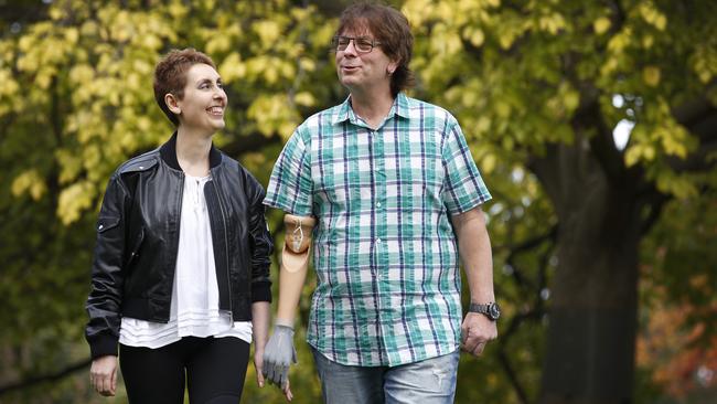 Alan Newey, holding hands with wife Kathy Dimitrio in the park, with his new mind-controlled robotic arm. Picture: David Caird