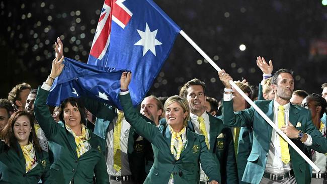 Australian flag bearer Mark Knowles (right) leads the team into the stadium during the opening ceremony at Carrara Stadium. Picture: DEAN LEWINS