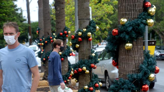 Christmas decorations line the trees as locals wear masks through the streets of Avalon. Picture: Jeremy Piper