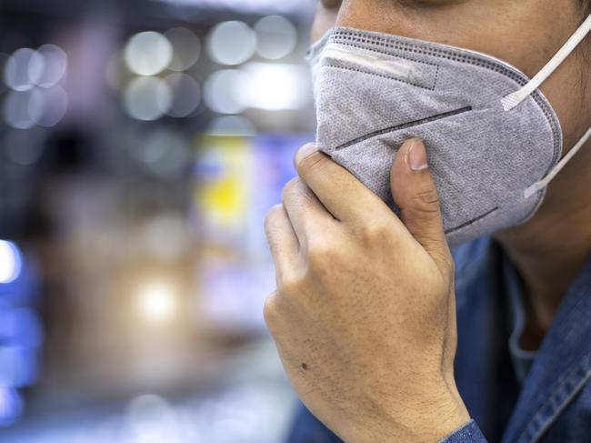 Close up portrait of a man using pm 2.5 pollution mask in the street of a big city.