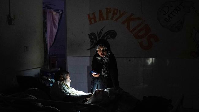 A woman uses a telephone torchlight as she stands next to a patient after a partial power cut at the Al-Aqsa Martyrs Hospital in Deir al-Balah on May 23, 2024, amid continuing battles between Israel and Hamas in the Gaza Strip.