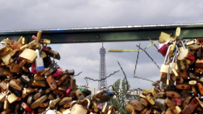 The Eiffel Tower appears through the partly lock-free railing of the famed Pont des Arts bridge in Paris where city authorities are taking down padlocks — just as they are on the Gold Coast.